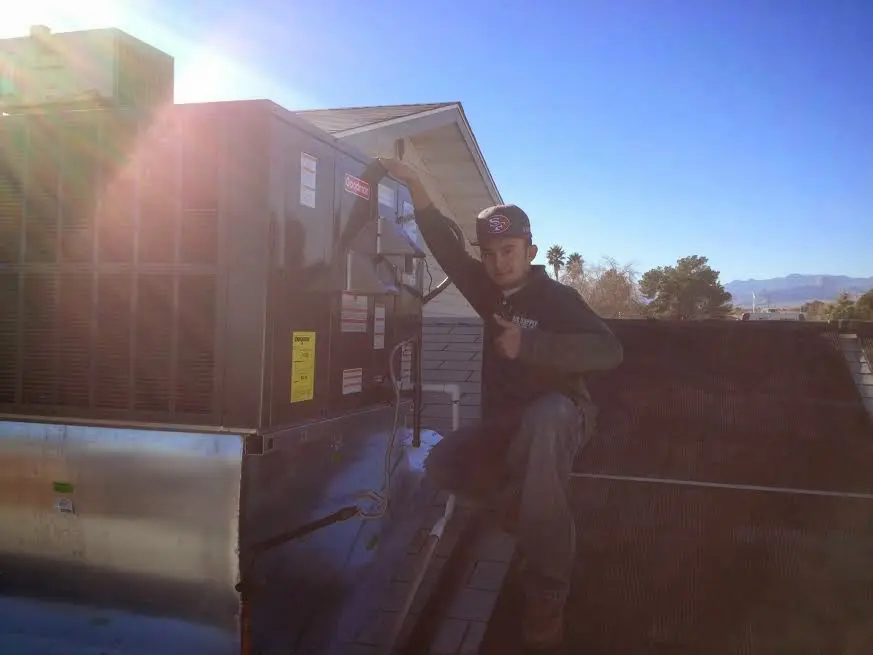 HVAC technician performing AC Tune-Up on a rooftop unit in Highland Park